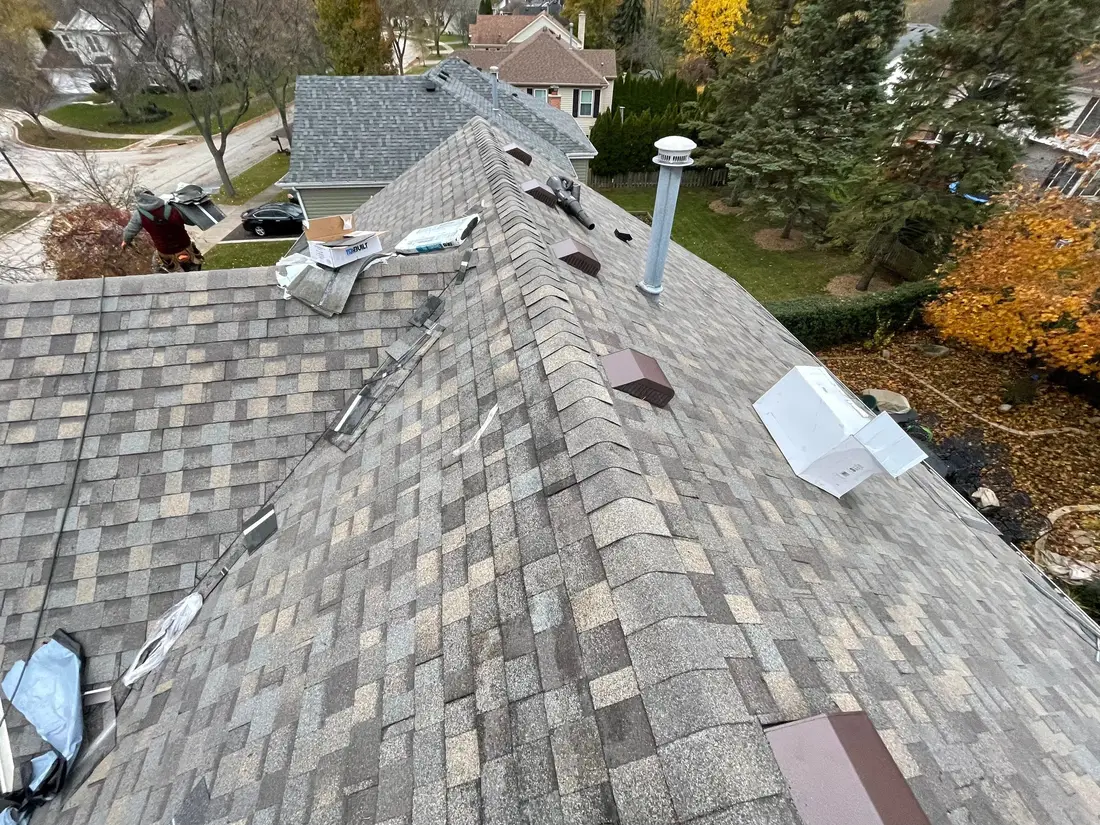 New architectural shingles half installed on a roof, with vents and roof jacks still in place