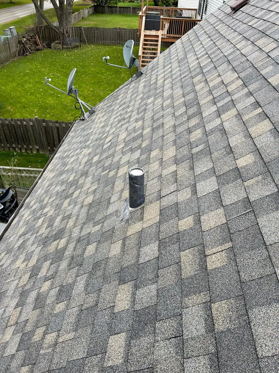 Plumbing vent pipe coming through a newly shingled slope with a fresh rubber boot