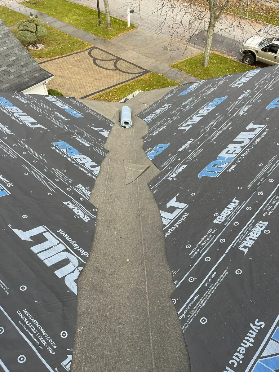 Dark self-adhering ice and water membrane laid down a roof valley between sheets of synthetic underlayment